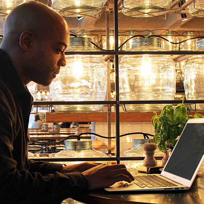 Jermaine working on his laptop with warm ambient lights in the background